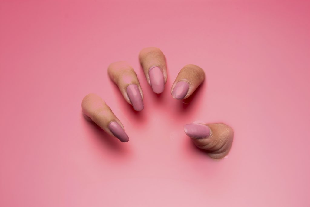 Unghie con smalto rosa su fondo rosa